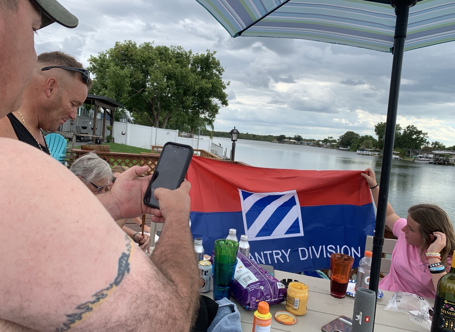 Friends displaying a 3rd Infantry Division flag beside a Florida lake
